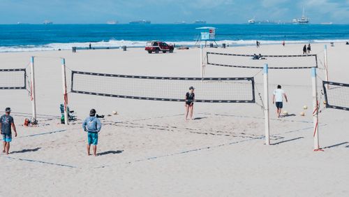 Free A fun beach volleyball game with players on a sunny day by the ocean. Stock Photo