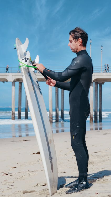 A Side View of a Man in Black Wetsuit Holding His Surfboard
