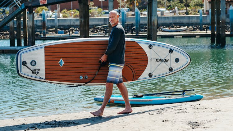 A Man Carrying A Paddleboard