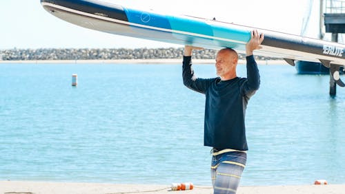 A Man in Black Long Sleeve Shirt Holding a Surfboard