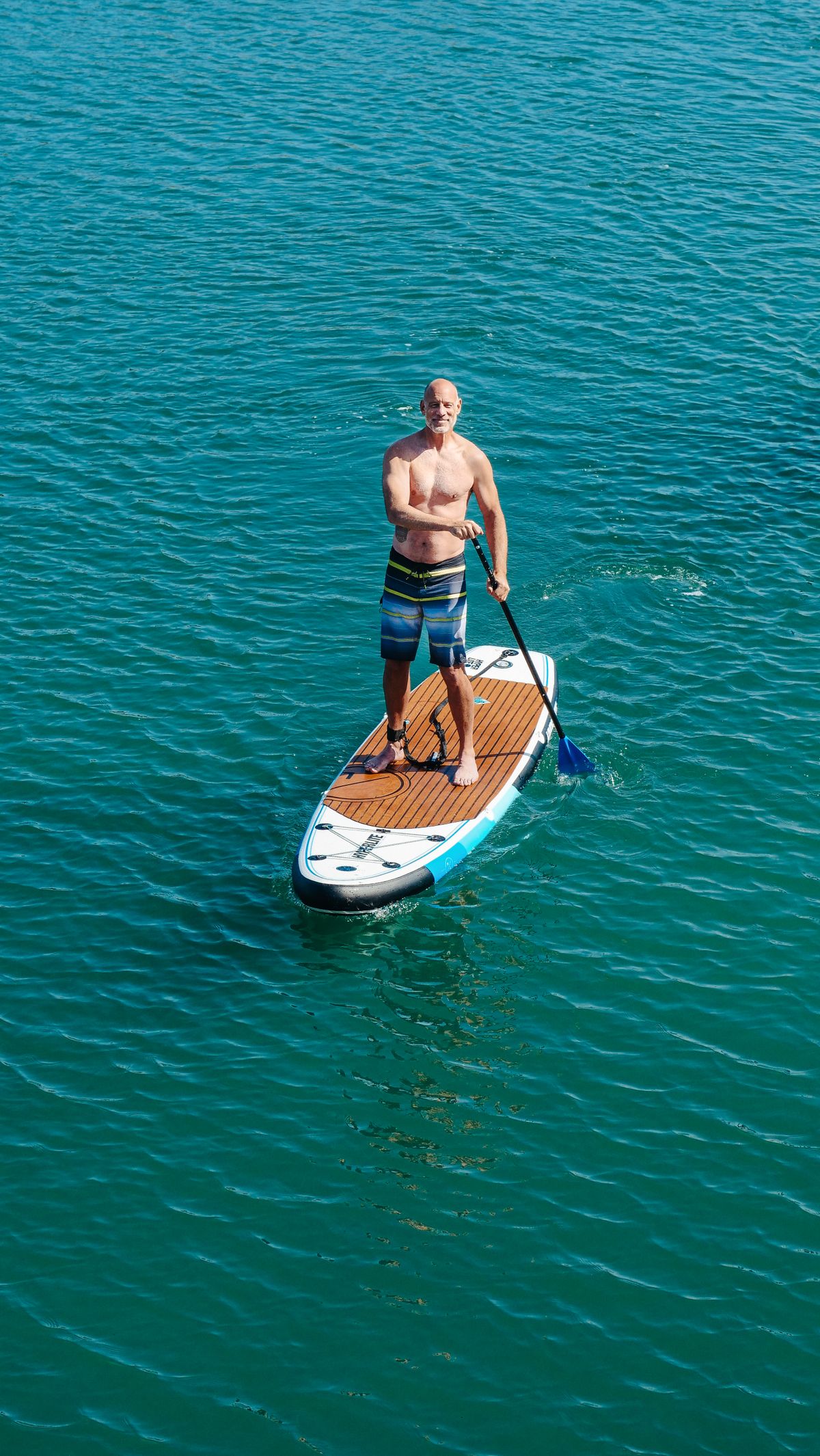 Aerial view of a paddle boarder on clear blue water