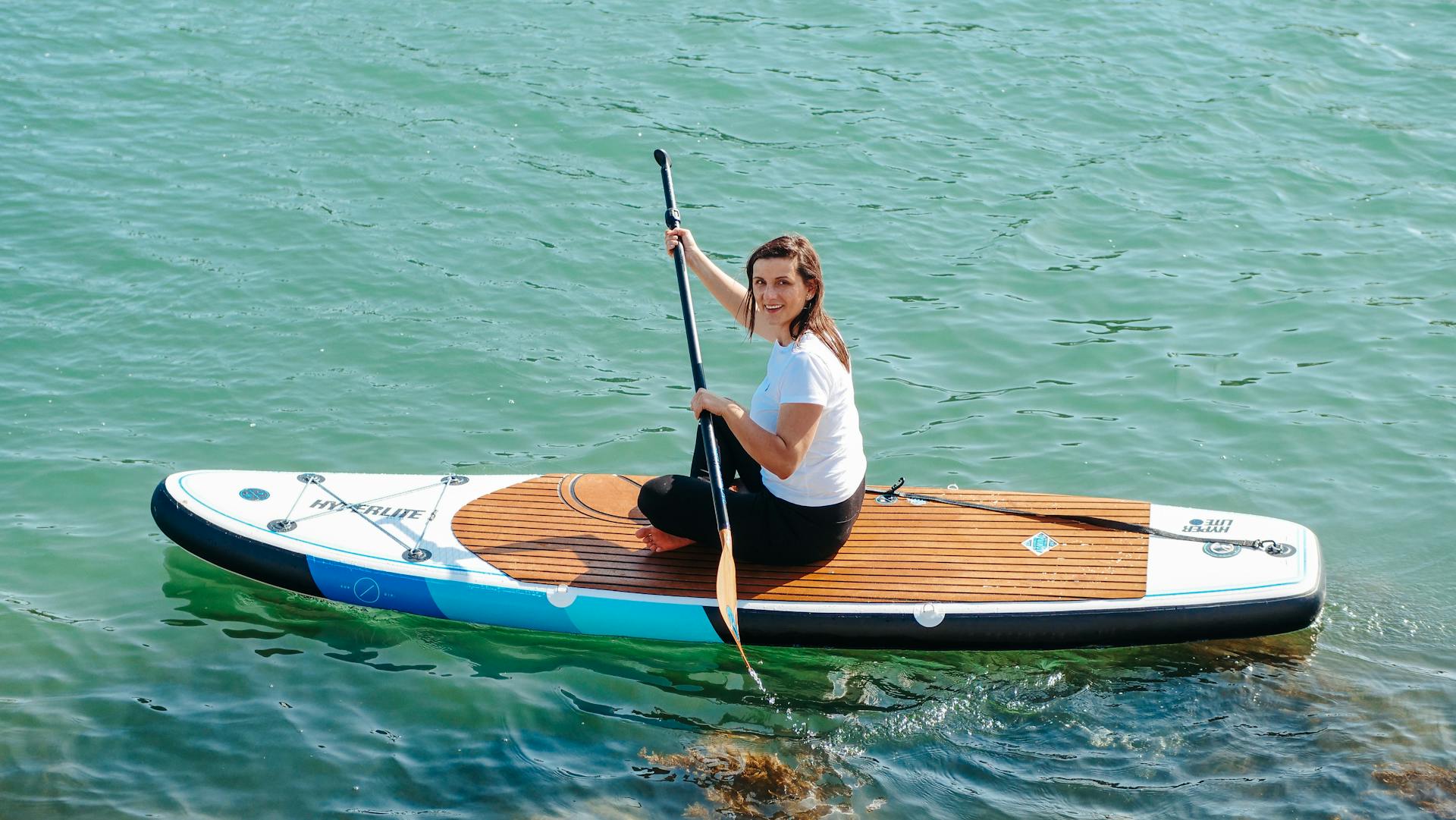 A Woman in White Shirt Riding on Sup Board