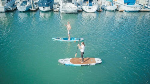 A Man and a Woman Paddleboarding in the Sea