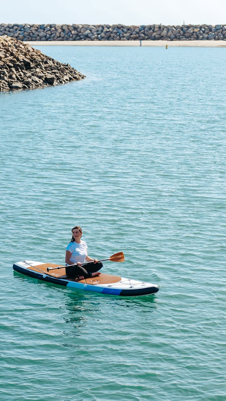 A Woman Sitting On A Paddleboard