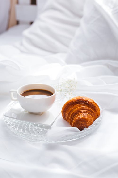 Free A White Cup with Coffee Beside a Croissant Stock Photo