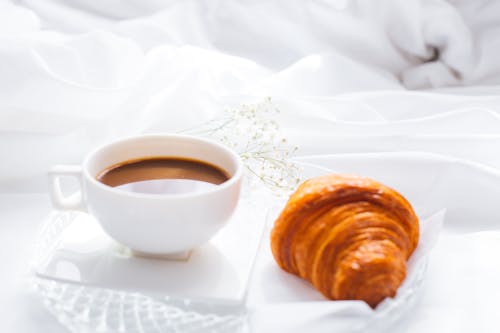 Free Close-Up Photograph of a Brown Croissant Beside a Cup of Coffee Stock Photo