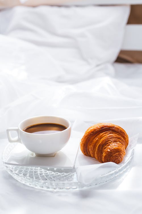 Free Photograph of a Cup of Coffee and a Croissant on a Glass Plate Stock Photo