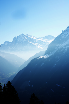 Snow-covered mountains with mist and clear skies symbolizing serene winter beauty.