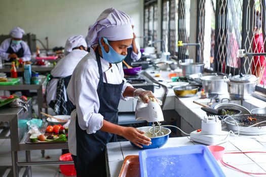 Culinary students in Indonesia learn food preparation techniques in a professional kitchen.