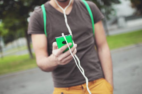Free Standing Person Using Green Smartphone Stock Photo