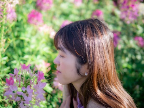 Side View of a Woman with Brown Hair Looking at Pink Flowers