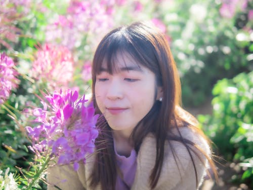 Selective Focus Photo of a Woman Looking at Purple Flowers