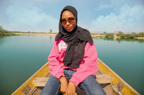 Photo of a Woman with Sunglasses Sitting on a Canoe