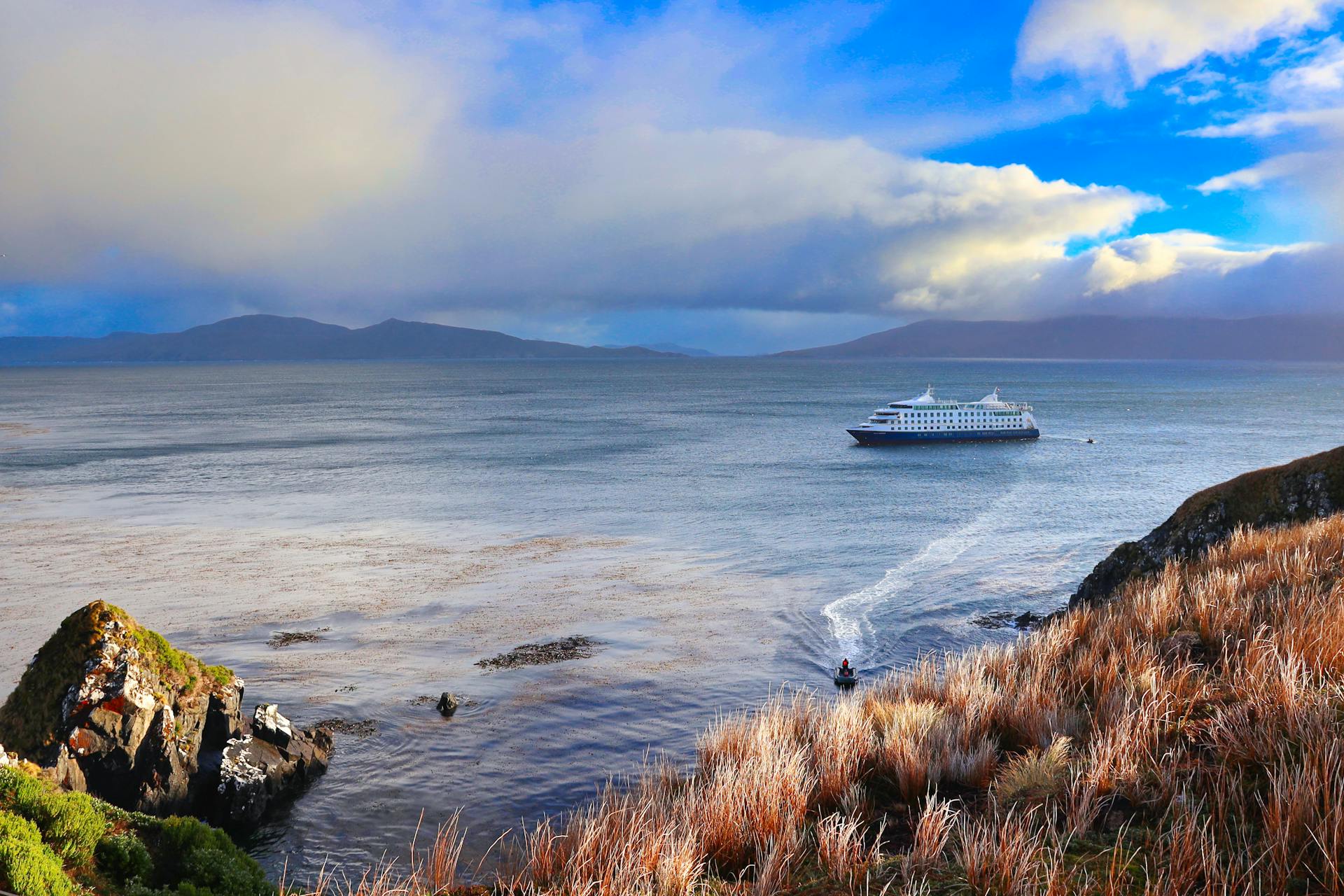 Picturesque cruise ship sailing near Cape Horn, Chile under dramatic skies.