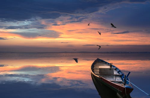 Free A Docked Boat and Flying Birds with a Scenic Sunset Stock Photo