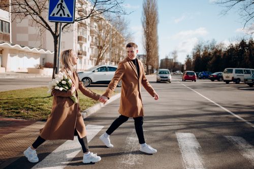 Free Happy couple holding hands and crossing a street in Belarus on a sunny day. Stock Photo