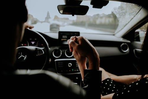 A Couple Holding Hands while Inside the Car