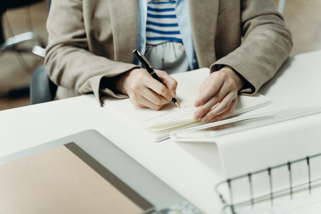 Person in Brown Blazer Writing on Notebook · Free Stock Photo
