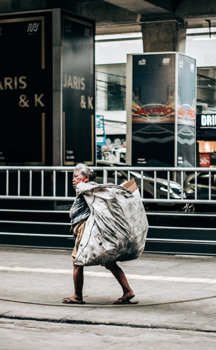 Elderly Woman Carrying A Dirty Sack 