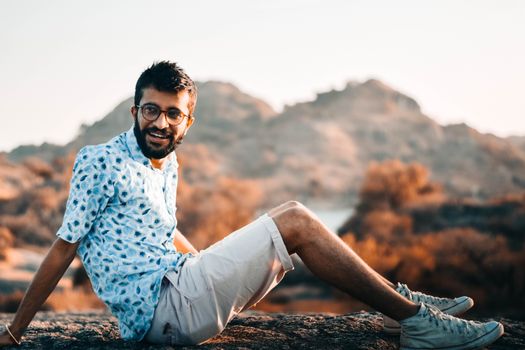 Smiling man in glasses enjoying sunlight outdoors, relaxed and cheerful.
