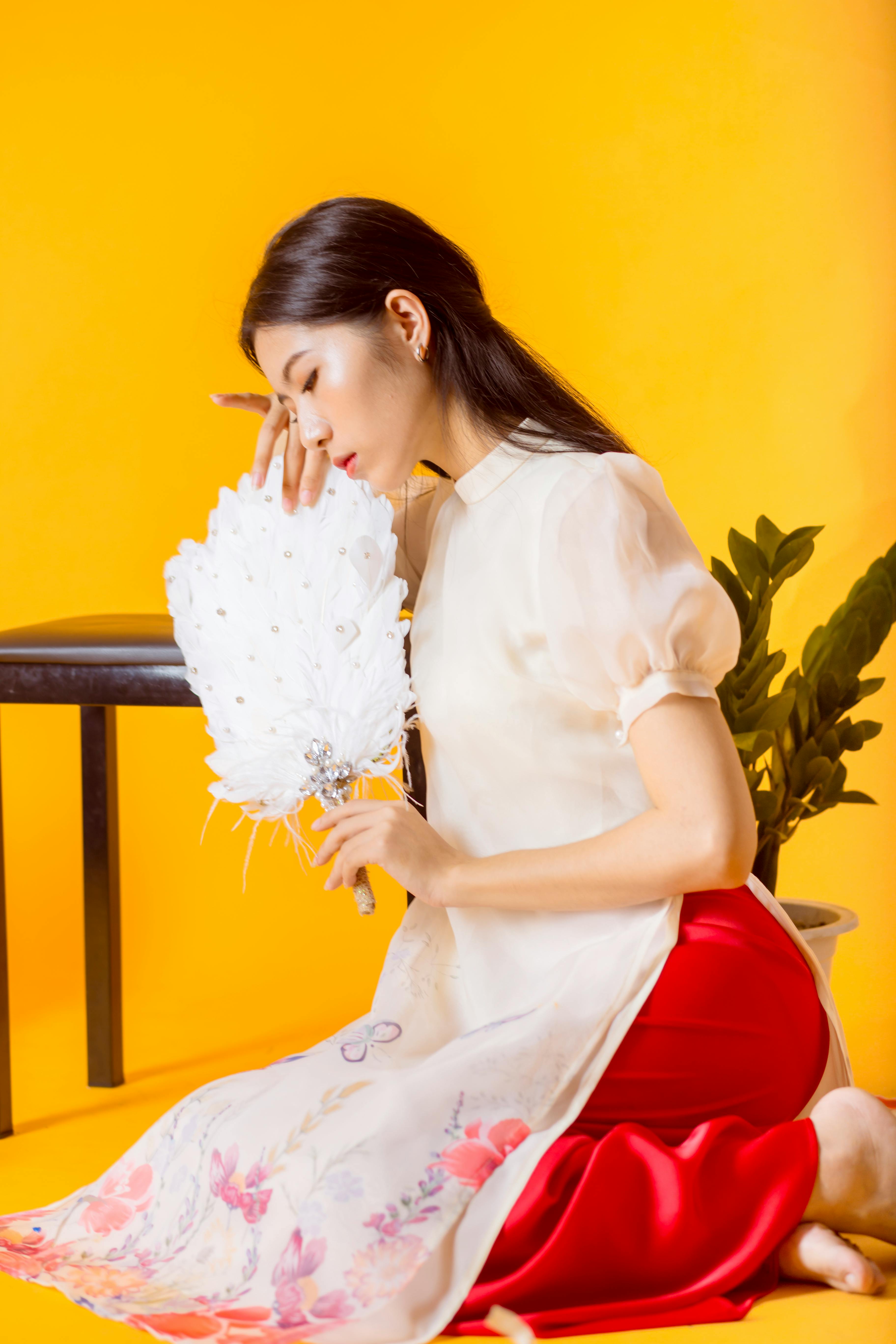 Woman in a Dress Touching Her White Hand Fan