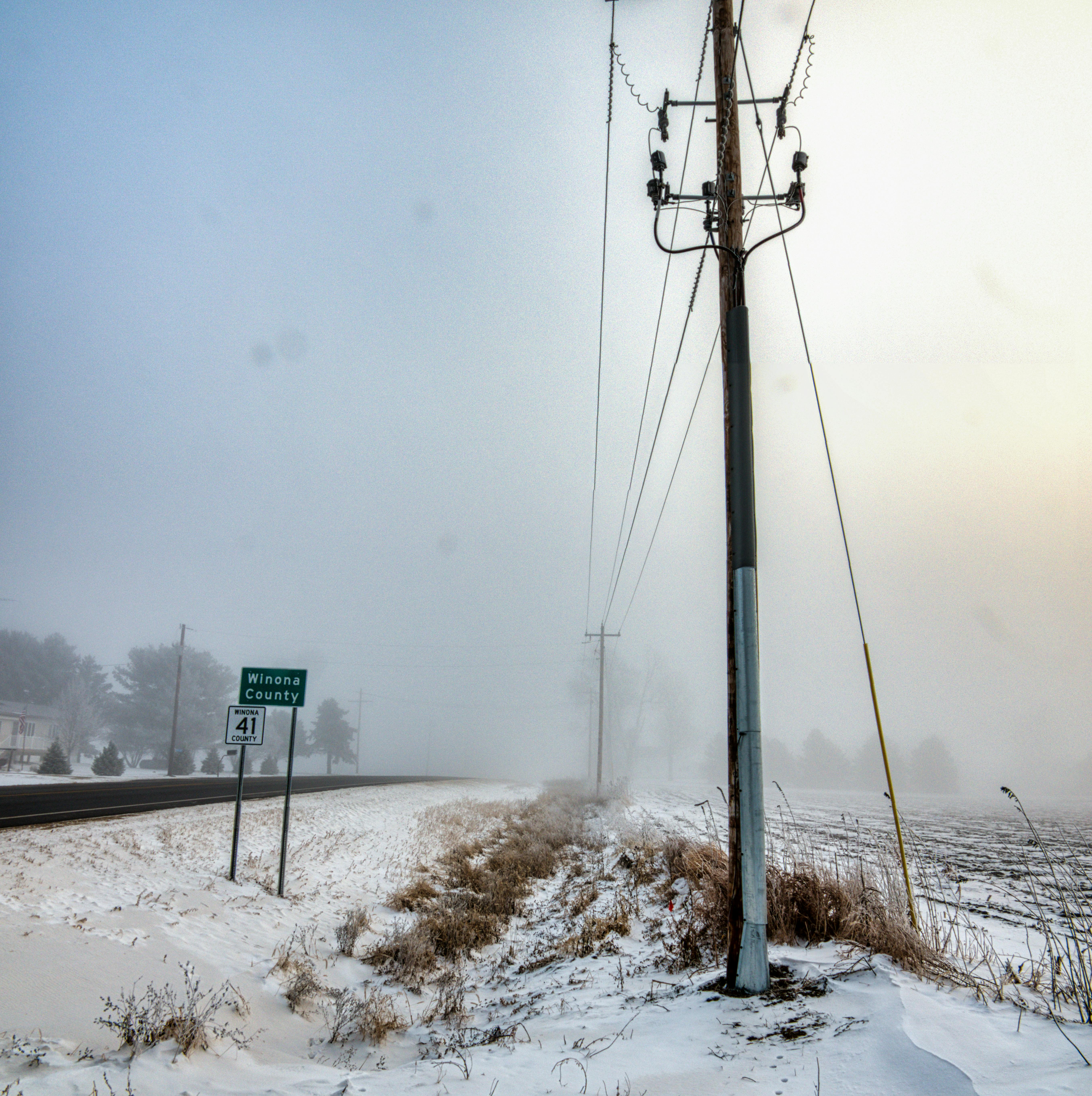 gray electric post on snow covered ground under gray sky