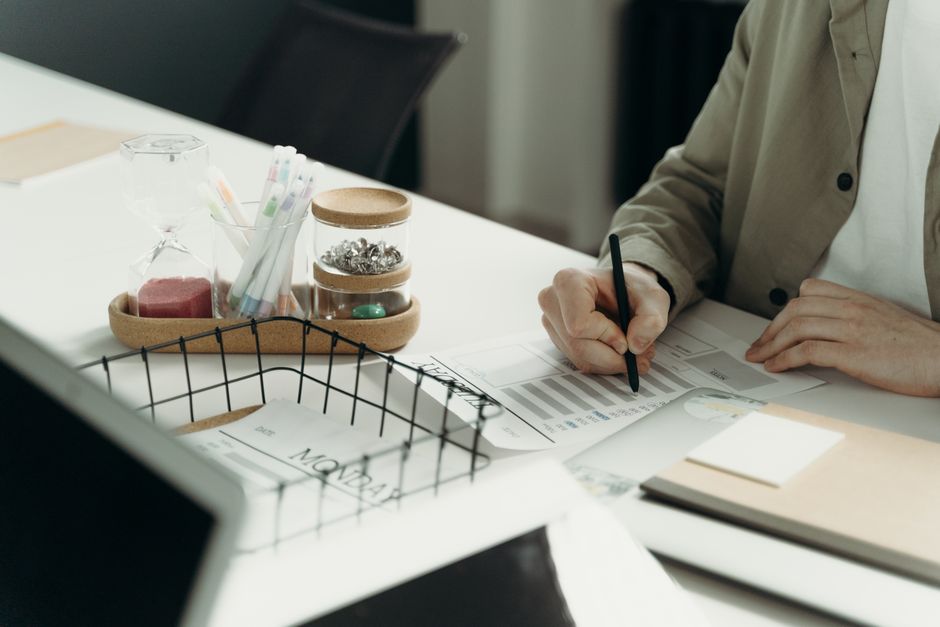 A person writing on a document at a tidy desk with office supplies.