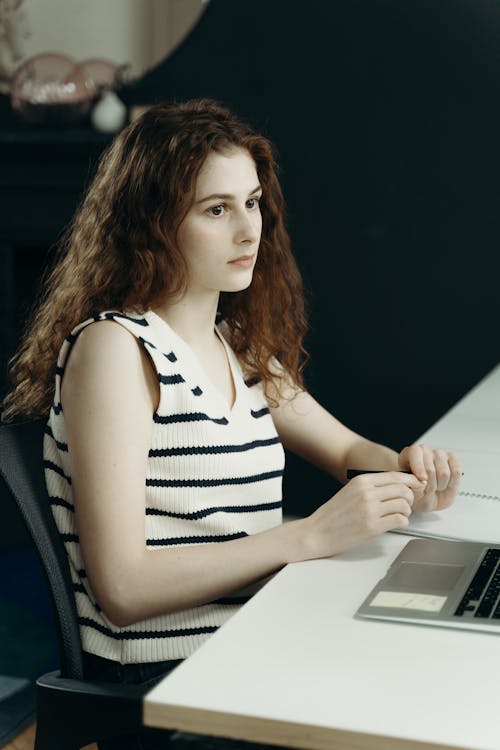 Woman in Black and White Stripe Top Sitting In Front of a Laptop