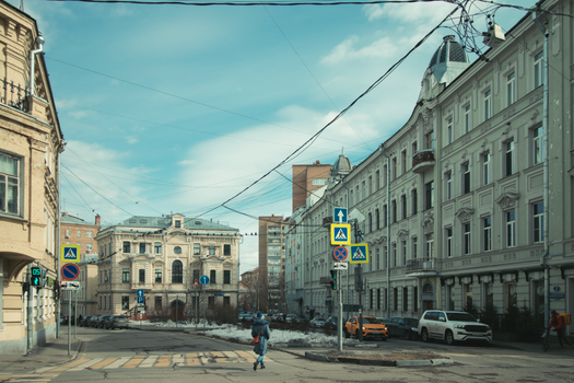Charming street intersection with historic buildings and parked cars under a blue sky.