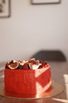 Red velvet cake topped with fresh figs, raspberries, and blueberries. Perfect for celebrations.