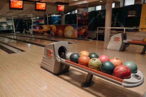 Free Vibrant bowling balls neatly arranged on a ball return system in an empty bowling alley. Stock Photo