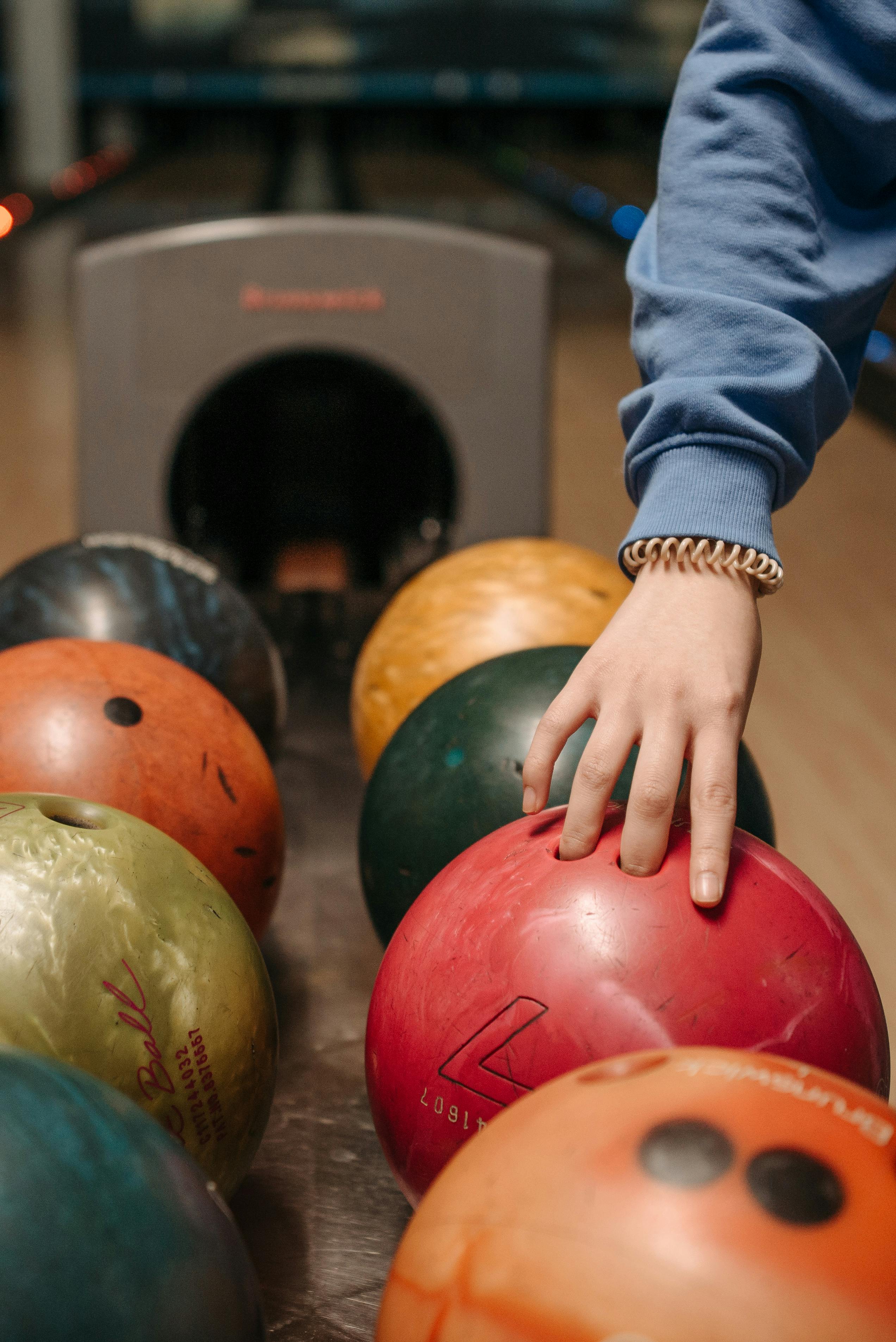 A Person Picking Up a Bowling Ball · Free Stock Photo