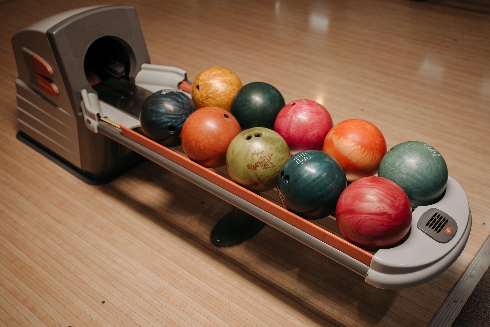 A vibrant array of bowling balls neatly arranged on a return system in a bowling alley.