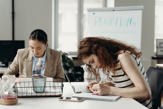 Two businesswomen working intently on planning projects in an office setting.