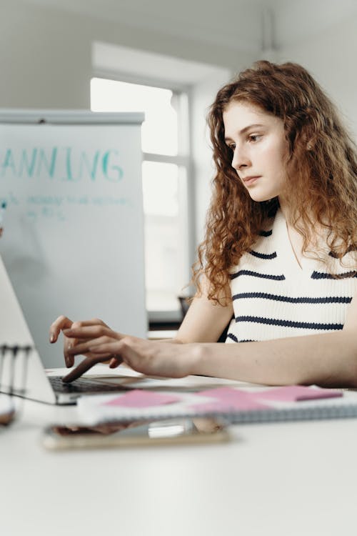 Woman in Black and White Stripe Top Using a Laptop 