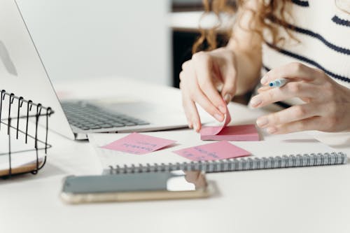 Free Person Writing on a Pink Sticky Note Stock Photo