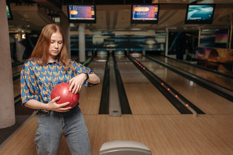 A Woman In Printed Shirt Holding A Bowling Ball