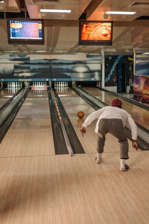 Free A person bowls indoor as the ball approaches the pins, capturing the essence of leisure and sport. Stock Photo