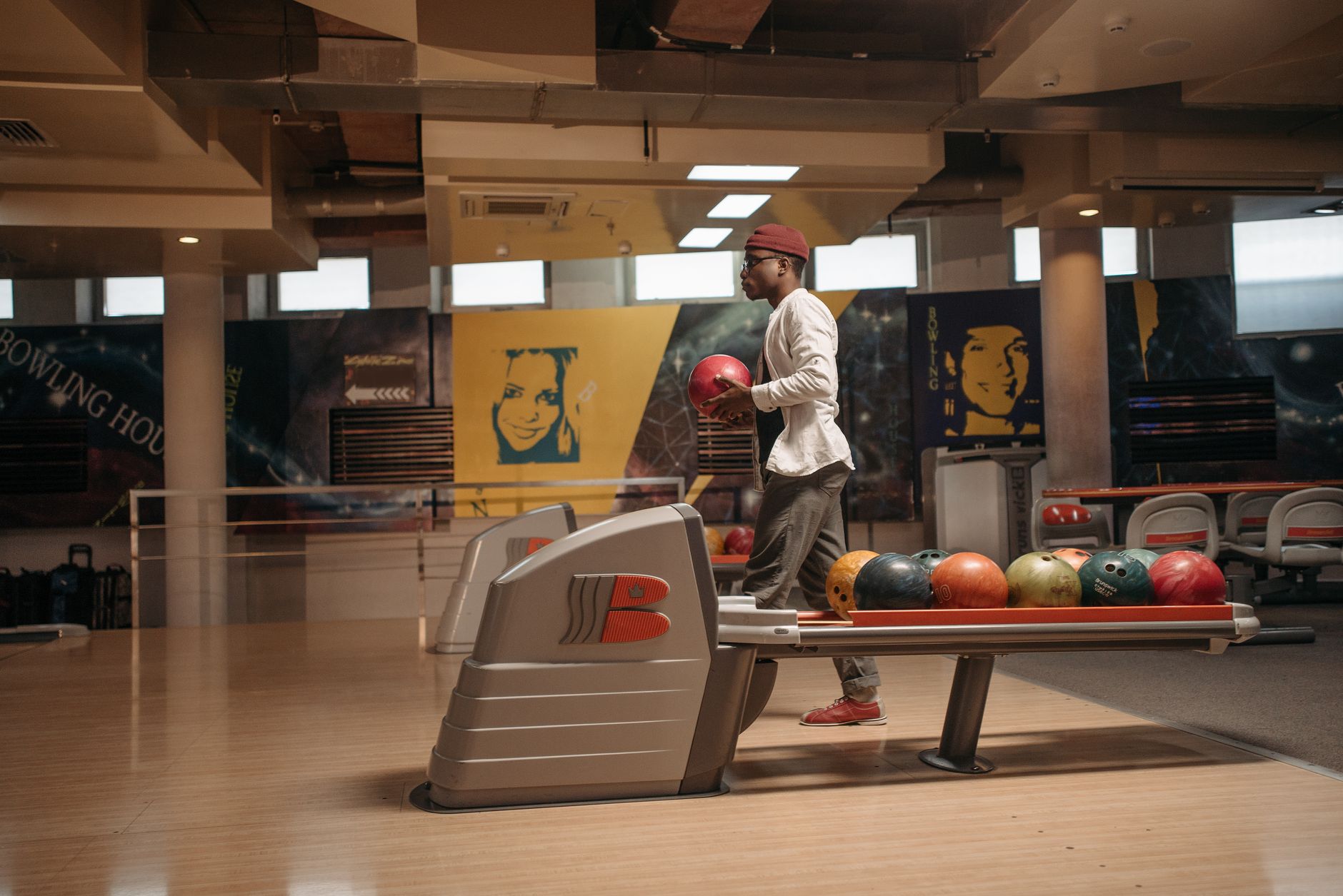 A man getting ready to bowl inside a stylish, modern bowling alley with colorful balls.