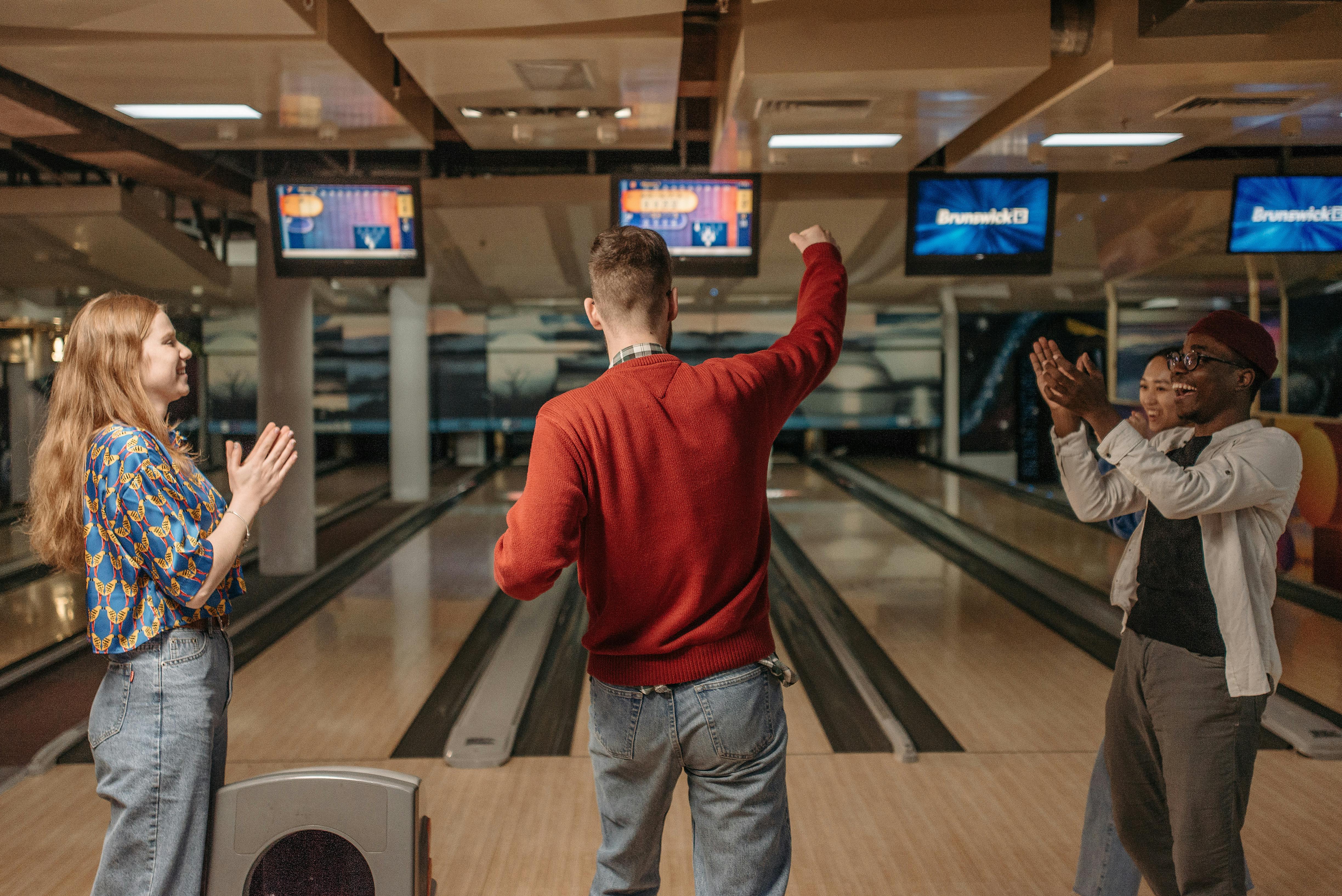 Friends celebrating a bowling game win at an indoor bowling alley.