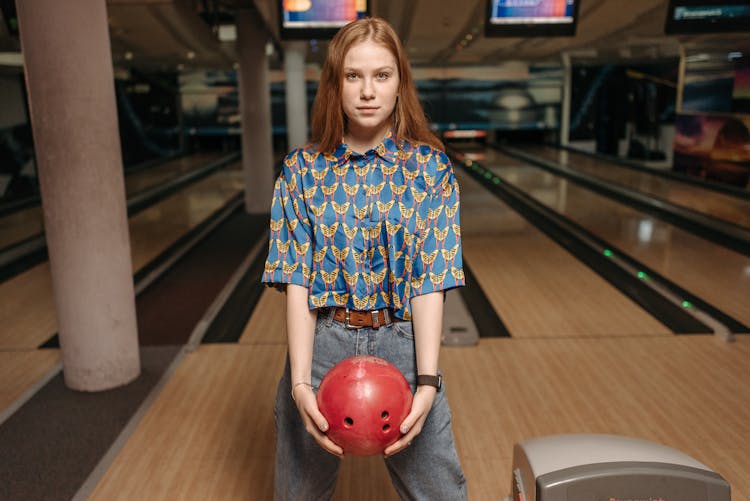 A Woman In Blue Printed Shirt Holding A Bowling Ball