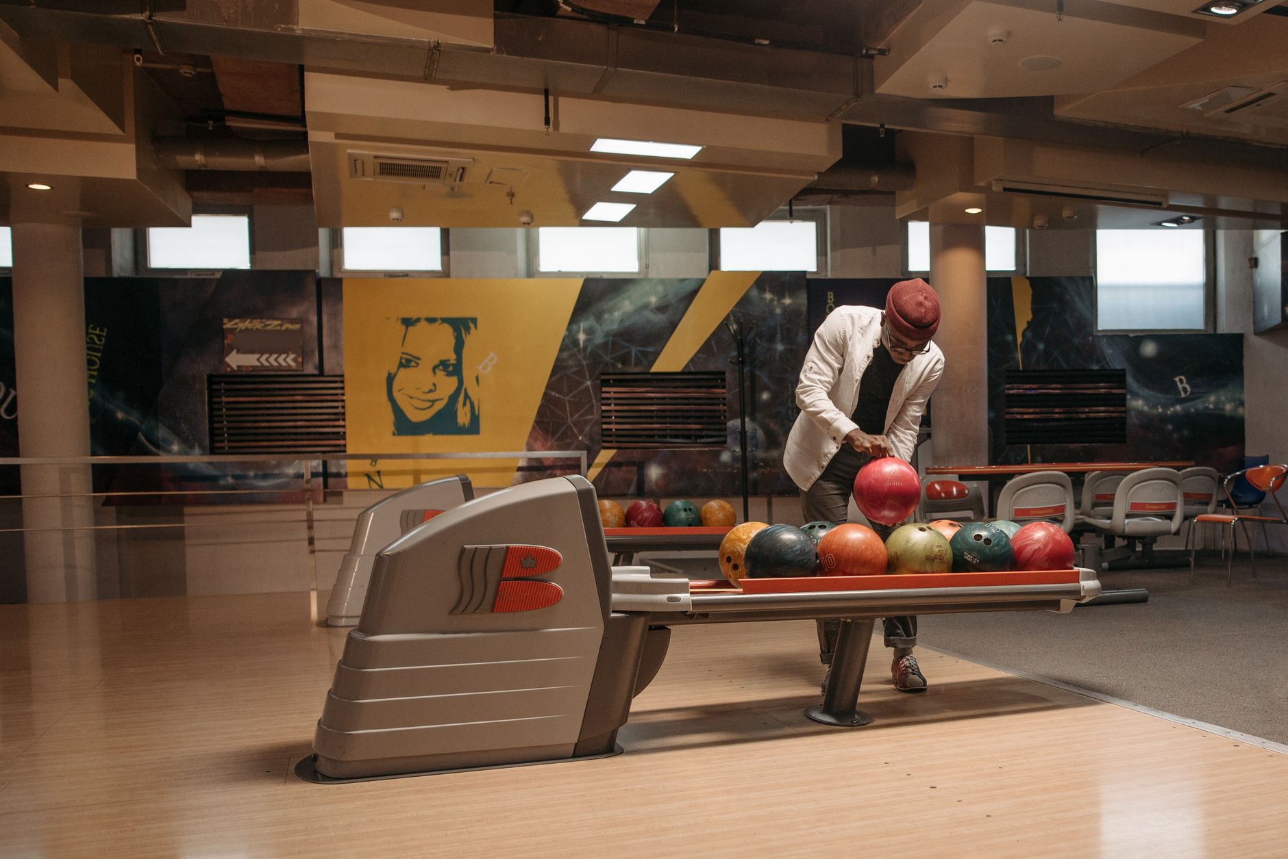 A man selects a bowling ball in a stylish and contemporary bowling center.