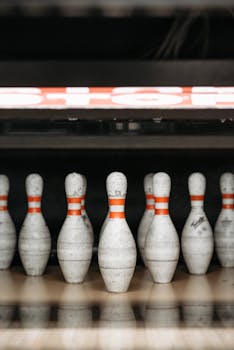 A row of bowling pins ready for a game on the alley floor indoors.