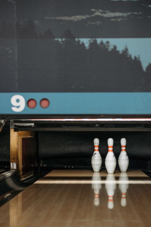 Free Three bowling pins stand at the end of a glossy bowling alley. Stock Photo