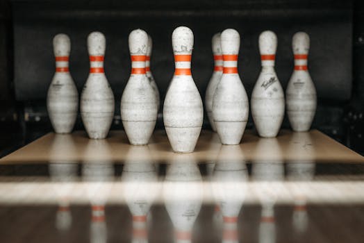 Focused close-up view of bowling pins lined up in an alley with reflections on the floor.