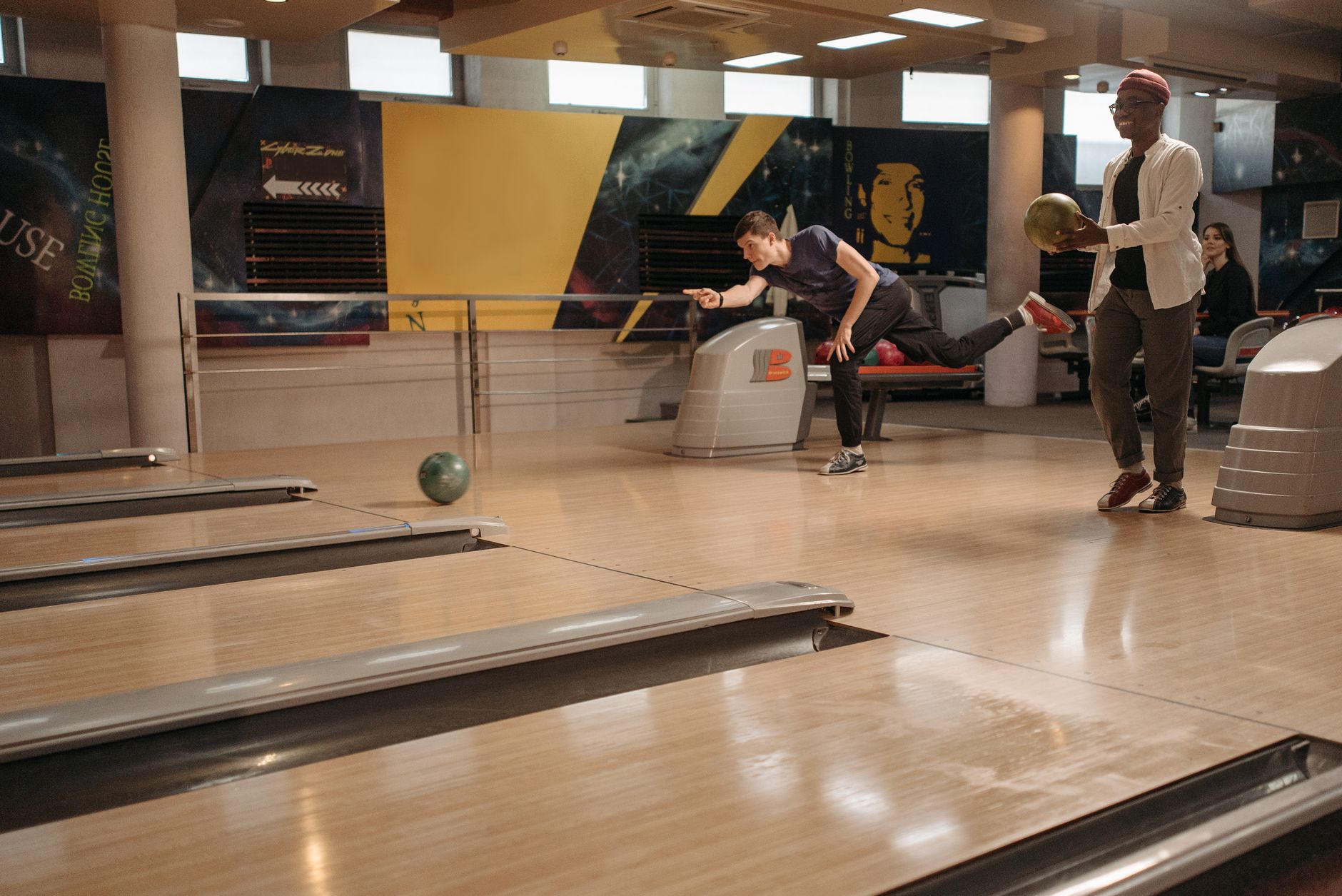 Two adults playing bowling indoors, highlighting leisure and sport in a fun atmosphere.