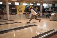 A young man throws a bowling ball in a lively modern bowling alley, enjoying leisure time.