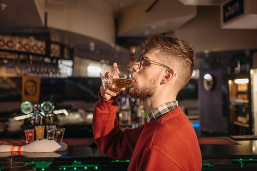 A Man Drinking an Alcoholic Beverage at the Bar Counter