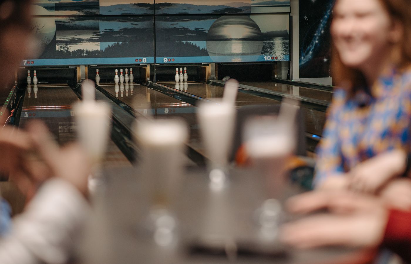 Adults enjoying a bowling night with milkshakes and laughter, adding fun to the sport indoors.