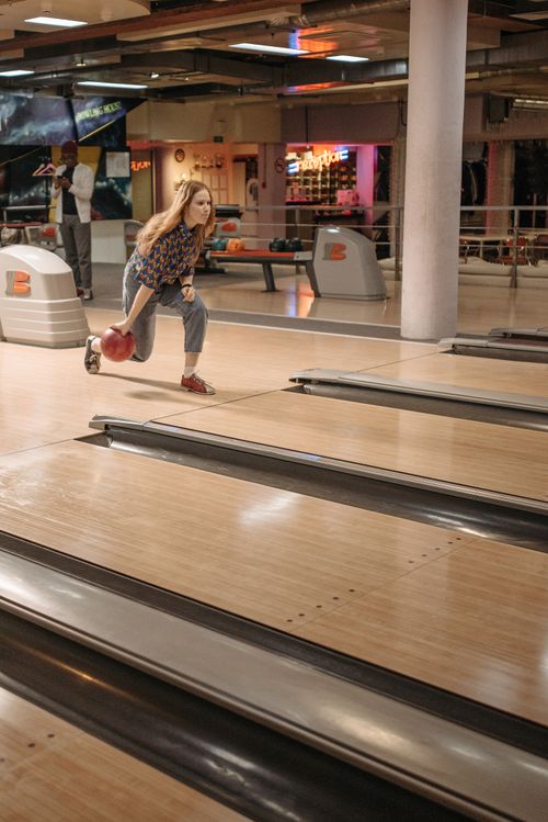 Free Adult woman releasing a bowling ball in a vibrant bowling alley. Stock Photo